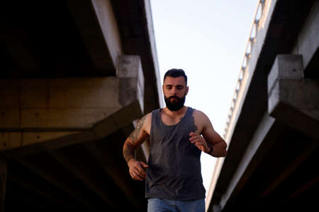 Young modern man with beard exercising outdoors in the streets to avoid crowding inside due to pandemic problemsの写真素材