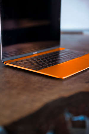Orange laptop on a beautiful wooden tableの写真素材