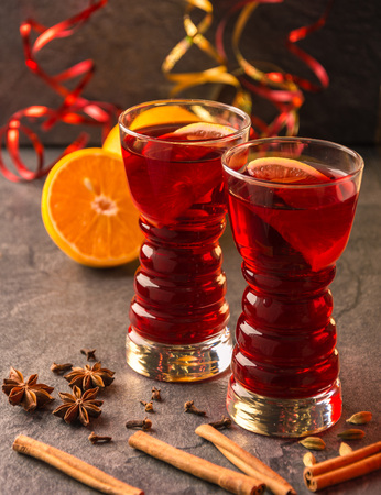 mulled wine with cinnamon sticks, oranges, star anise and  shiny gold ribbon on a dark tableの写真素材