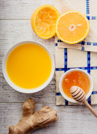 oranges, orange juice with honey and ginger lie on a white wooden table top viewの写真素材