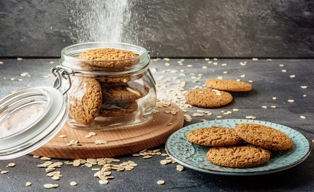 Oat cookies lay on a plate and bank with oatmeal cookies standing on a wooden board.の写真素材