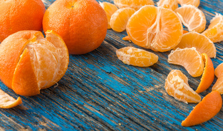 mandarines, peeled tangerine and tangerine slices on a blue wooden tableの写真素材