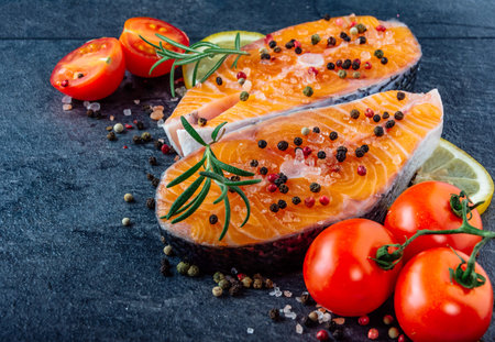 Delicious salmon steak , rich in omega 3 oil, with aromatic herbs and spices with a lemon, tomato,...