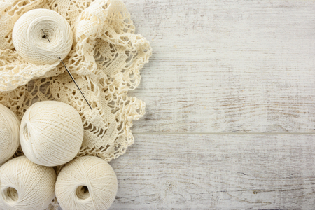 crochet tablecloth, crochet hooks and balls of cotton thread on a white wooden table. top view, copy spaceの写真素材