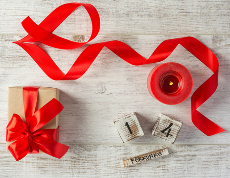 Box with a present to the Valentine's Day ,wooden calendar, red candle and tape on a white wooden table. Top view.の写真素材