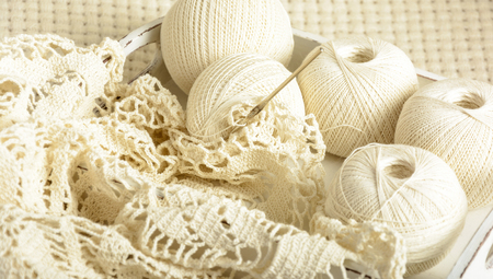 crochet tablecloth, crochet hooks and balls of cotton thread on a white woolen plaidの写真素材
