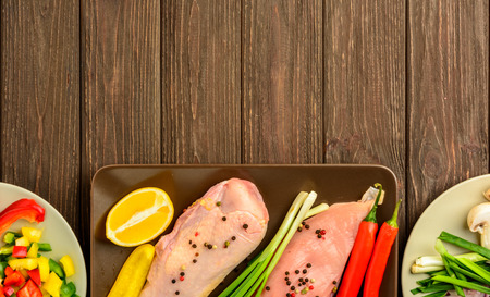 The chicken fillet and vegetables prepared for frying on a brown wooden background. Top view, copy space.の写真素材