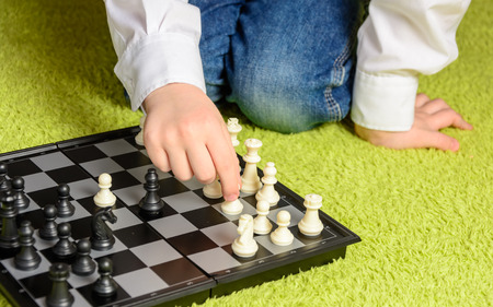 child playing chess sitting on the carpetの写真素材