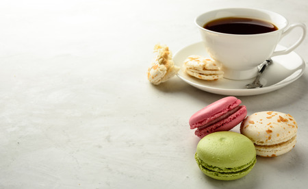 Cup of black tea with varicolored macaroons  on a white background in light key. Copy space.の写真素材