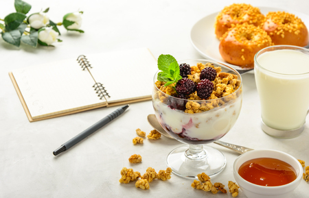 Delicious and healthy breakfast of granola, buns brioche, honey and black tea on a light background . Soft focus.の写真素材