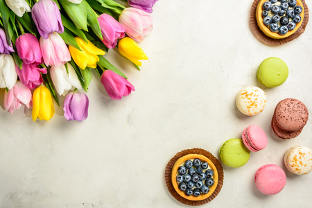 Beautiful festive bouquet of tulips and cakes on white background. Flat lay. Copy space.
の写真素材