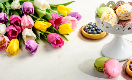 Beautiful festive bouquet of tulips and cakes on white background. Copy space.の写真素材