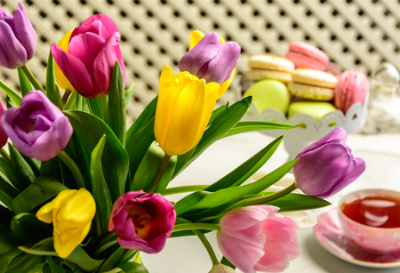Beautiful festive bouquet of tulips and cakes on white backgroundの写真素材