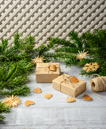 Christmas festive card with fir branches and gift boxes  on the white wooden background .  Space for an object.の写真素材