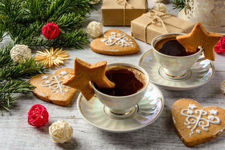 Christmas festive card with fir branches and gift boxes,two cups of coffe and cakes on the white wooden background .の写真素材