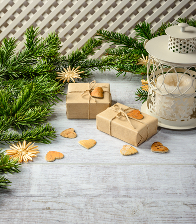 Christmas festive card with fir branches and gift boxes  on the white wooden background .  Space for an object.の写真素材
