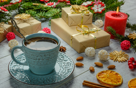 Christmas festive card with fir branches, cup of coffee and festive decor on the white wood backgroundの写真素材
