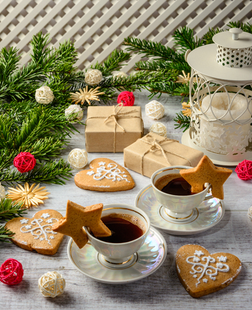 Christmas festive card with fir branches and gift boxes,two cups of coffe and cakes on the white wooden background .の写真素材