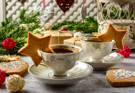 Christmas festive card with fir branches and gift boxes,two cups of coffe and cakes on the white wooden background .の写真素材