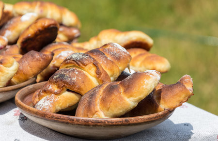 Fresh buns and cupcakes are on the table that is situated outdoors. This is dishes of the Ukranian...