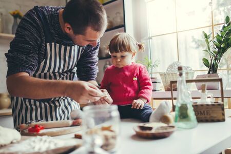 Happy family in the kitchen. Father and daughter are preparing the christmas cookies.の写真素材