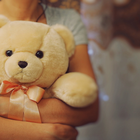 A girl is holding and hugging a teddy bear. Concept idea - goodbye to childhood. Vintage style. Place for your textの写真素材