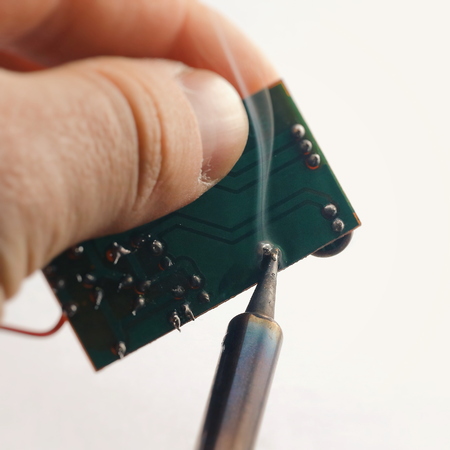 soldering contact on a printed circuit board, isolated image on a white background, macro shooting, smoke from a soldering tip.の写真素材