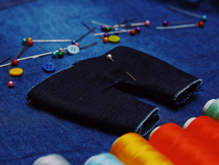 Background jeans fabric, thread, needles with threads, colorful background. Concept sewing business, business fabrics, sewing workshop. Place for text.の写真素材