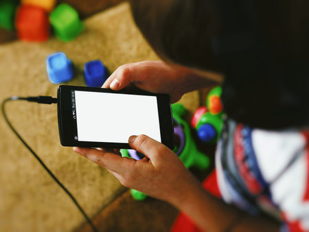 Top view of boy with headphones holding mobile smart phone. Smartphone. Place for text - a white...