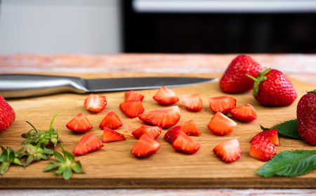 Slices of ripe strawberries on a cutting board in the kitchen. Preparing dessert or lemonade with fresh strawberries. selective focus.の写真素材