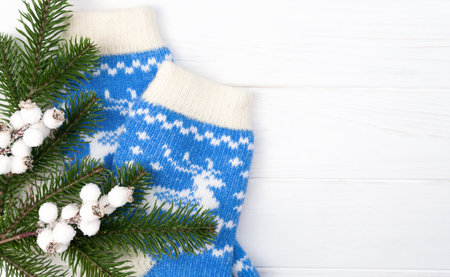 Festive flatlay composition with a fir branches, Christmas decor and knitted socks on a white wooden background. Top view. Copy space. Selective focus.の写真素材