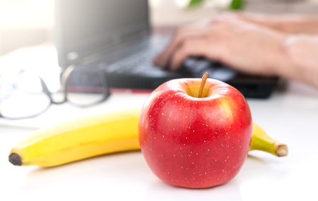 A red apple and banana on the desktop. The concept of a healthy food at work. Close-up. Selective focus.の写真素材