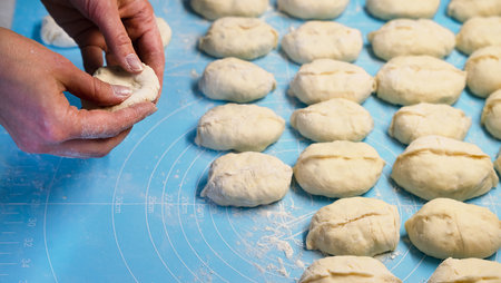 Woman's hands sculpt pie with potatoes and meat in the kitchen. The process of making homemade pies. Close-up. Selective focus.の写真素材