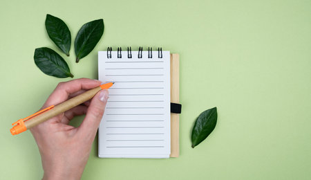 Young woman using a notepad and pen made of eco friendly materials. Top view. Banner. Place for...