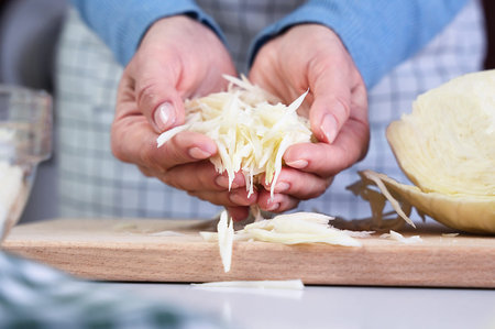 Cooking diet salad, preparation of ingredients. Woman's hands hold chopped cabbage. Close-up....