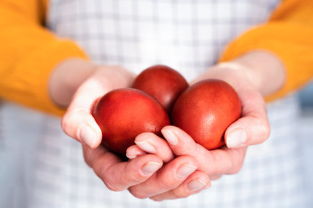 Woman's hands hold red Easter eggs. Coloring eggs with natural dyes. Close-up. Selective focus.