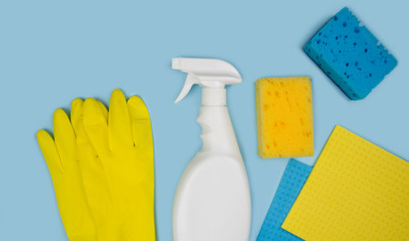 Detergent, rubber gloves, kitchen sponges and rags on a blue background. Cleaning concept. Banner....