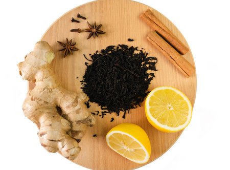 A black dry tea, ginger, lemon and cinnamon isolated on white background. Tea drinking concept. Top...
