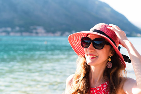 A smiling woman in red hat and red dress on the sea. Place for text. Close-up.の写真素材