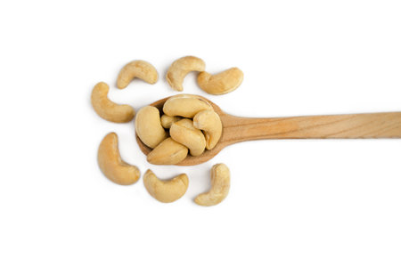 Cashew nuts in wooden spoon isolated on white background. Top view. Close-up. Selective focus.の写真素材