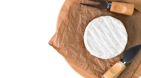 Camembert cheese and knives for cutting cheese on craft paper isolated on white background. Top...