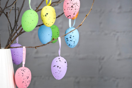 Easter composition. Multi-colored decorative eggs hang on the branches in a vase on the table. Copy...