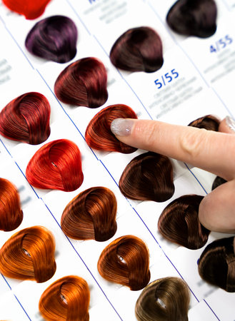 A woman points to a hair color on a palette with hair dye samples. Close-up. Selective focus.の写真素材