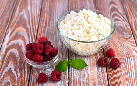 Fresh raspberries and cottage cheese on the wooden kitchen table. Healthy breakfast. Close-up. Copy space.の写真素材
