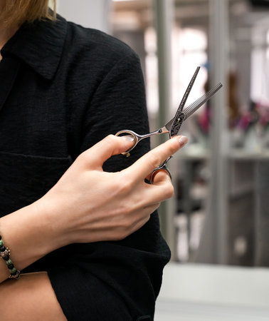 Hand of girl hairdresser stylist holds scissors. Hair care concept in a beauty salon. Selective...