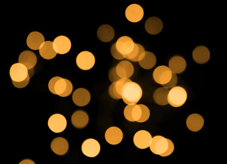 Golden bokeh lights in blur on black background. Selective focus.の写真素材