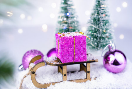 Christmas or New Year card. Christmas gift on a decorative sleigh on the snowy background. Close-up. Selective focus.の写真素材