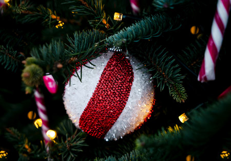 Festive Christmas ornament with a round bauble with a bold red and white striped. The atmosphere feels cozy and magic. Close-up. Selective focus.の写真素材