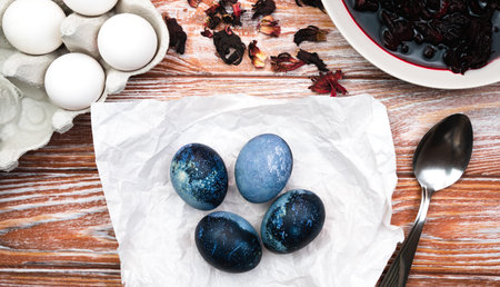Easter eggs painted blue on a wooden kitchen table. The process of dyeing eggs with natural food...