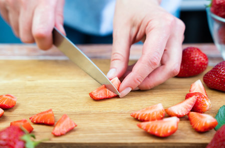 Woman cutting strawberry for lemonade on the table in the kitchen. Close-up. Selective focus.の写真素材